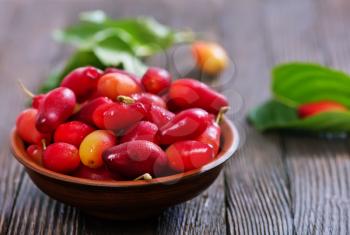 cornelian cherry berry in bowl on wooden background