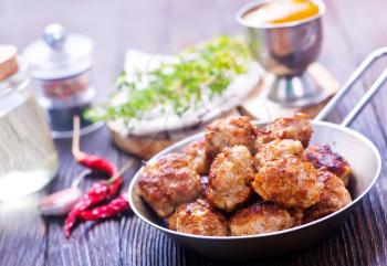 fried meat balls in pan and on a table