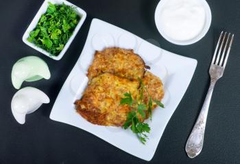 Zucchini pancakes on white plate and on a table