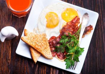Breakfast on a table, fried bacon and eggs on plate
