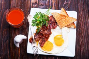 Breakfast on a table, fried bacon and eggs on plate