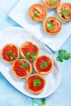 tartalets with salmon fish and caviar on a table