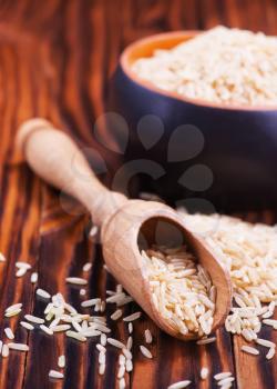 raw rice in wooden spoon and on a table