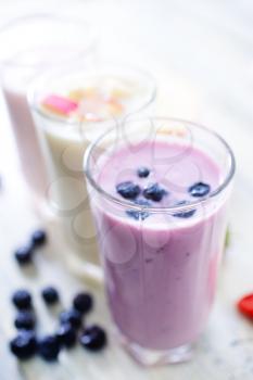 yogurt with fresh berries in glass and on a table
