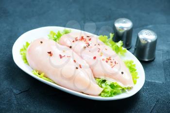 raw chicken fillet on the plate and on a table