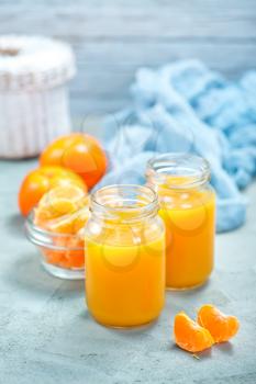 tangerines juice in glass bank and on a table