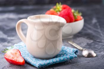 milk in jug and strawberry on a table
