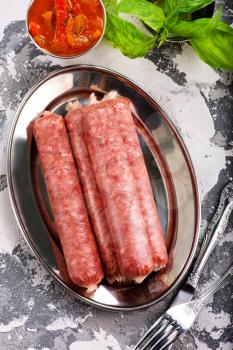 raw sausages on metal plate and on a table