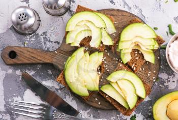 bread with avocado on board and on a table