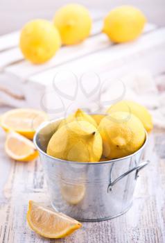 fresh lemons in metal bowl and on a table