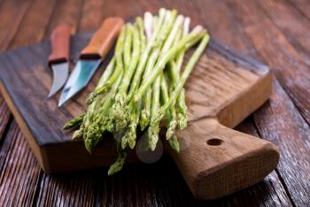 green asparagus on board and on a table