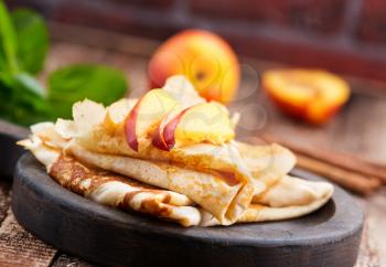 pancake with peach and cinnamon on the wooden board
