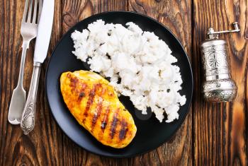 boiled rice with chicken breast on plate on a table