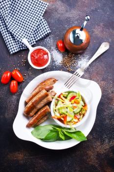 grilled sausages with salad on white plate, stock photo