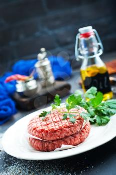 raw burgers on white plate with spice and salt