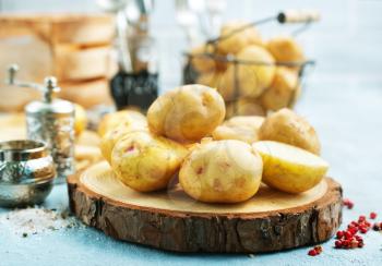 raw potato, potato on wooden board on a table