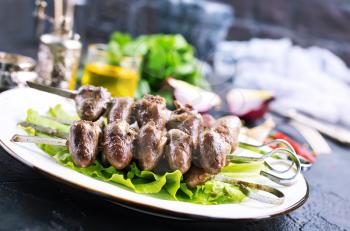 Fried hearts with spice. Chicken hearts kebab with salad on a plate top view