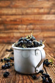 black currant in metal cup and on a table