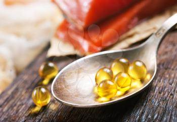 Fish oil capsules with omega 3 on wooden board
