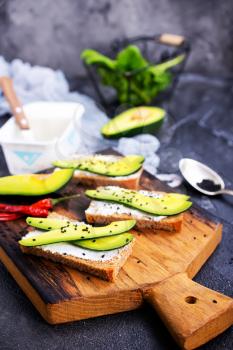 bread with cheese and with avocado on wooden board