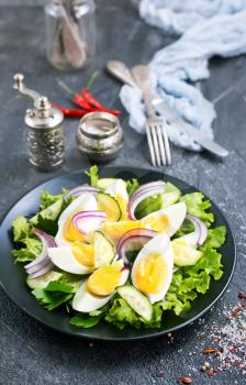 salad with boiled eggs on black plate