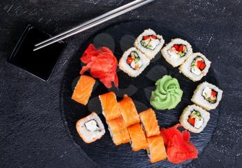 Japanese sushi on a rustic dark background. Sushi rolls and ginger, wasabi, soy sauce. 