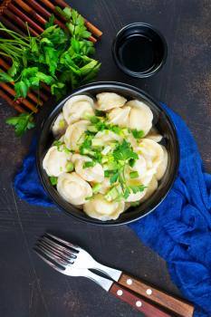 pelmeni in bowl, boiled pelmeni with fresh greens and sult