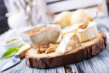 cheese nuts honey and fresh pears on wooden board
