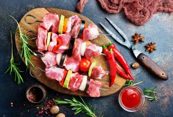 raw kebab with vegetables on wooden board