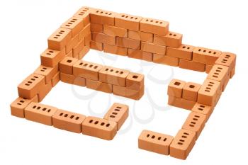 Red brick construction in the shape of a house under construction on isolated white background