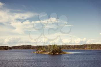 Ladoga lake with small island under summer sunset light panoramic view. Toning effect done with a vintage retro Instagram style filter