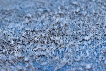 White hoarfrost crystals on flat surface closeup macro view with selective focus, shallow depth of field, nature background.
