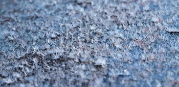 White hoarfrost crystals on flat surface macro view with selective focus, shallow depth of field, nature background.