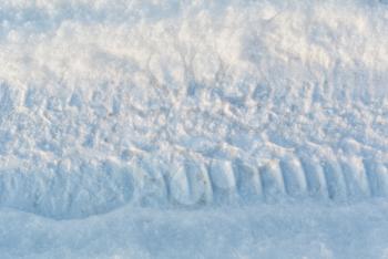 Car tire tracks and footprint on white winter snow close-up view, winter background