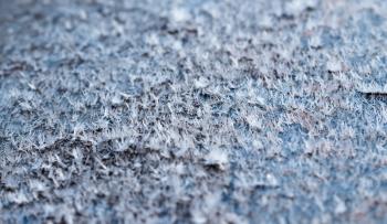 White hoarfrost crystals on flat surface closeup macro view with selective focus, shallow depth of field.