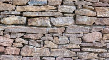 Old aged stone wall texture background made with natural stones bricks with cracks closeup view