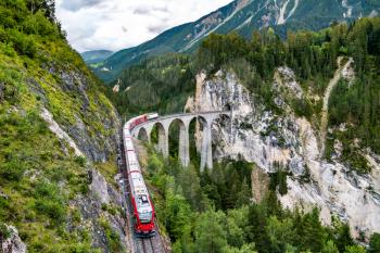 Passenger train crossing the Landwasser Viaduct in the Swiss Alps