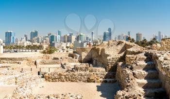 Ruins of Bahrain Fort with Manama skyline. A UNESCO World Heritage Site in the Middle East