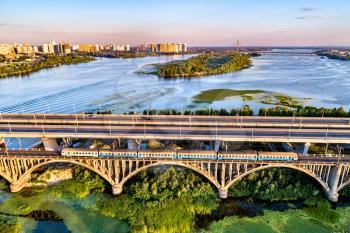 Aerial view of a Kiev Urban Electric Train crossing the Dnieper by the Darnytsia Bridge. Ukraine, East Europe