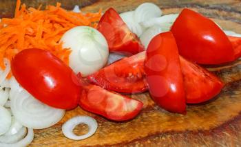 Sliced tomatoes, carrots and onions on a wooden background