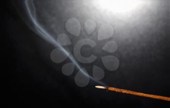 Incense stick with smoke on a dark background