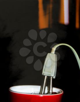 Kettle and cup with steam on dark background