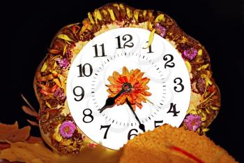 Imaginative flower clock on yellow leaves on a dark background