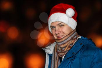The young man in a Santa hat on a dark background