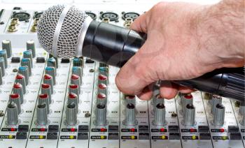 Hand with a microphone on the audio mixer