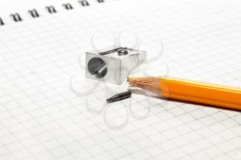 A broken pencil and a pencil sharpener on a notebook