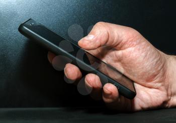 Hand with a modern mobile phone on a dark background
