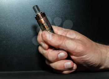 Hand with electronic cigarette on a dark background