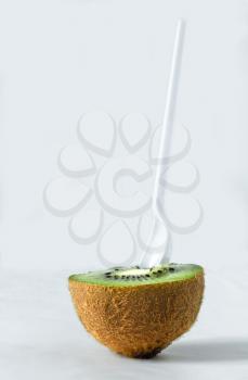 Half kiwi with a spoon on a light background