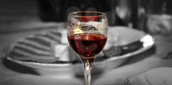 A colored glass of wine with a lipstick print on a black and white background of a festive table